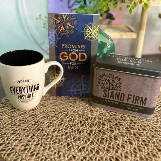 Mug, book, and tin on a textured surface with plants in the background