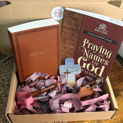 Box containing a brown leather Bible, a book titled 'Praying the Names of God', and decorative items on a wooden surface.