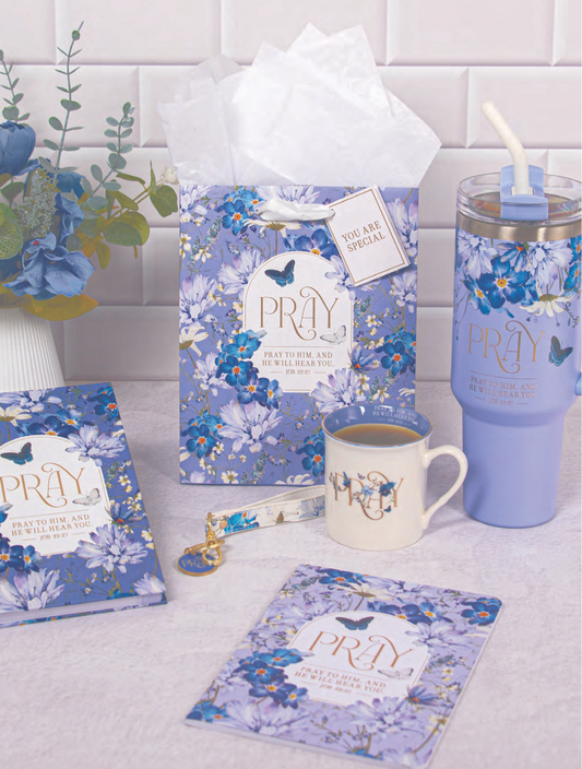 Blue floral-themed products including a mug, tumbler, and books on a white surface with a tiled wall background.