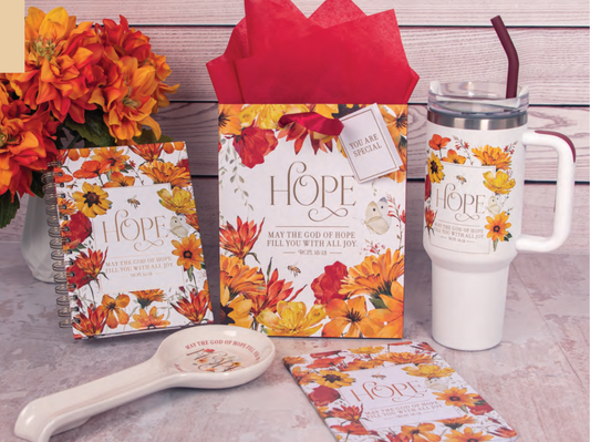 Collection of 'Hope' themed products including mug, notebook, and keychain on a table with autumn-themed design.