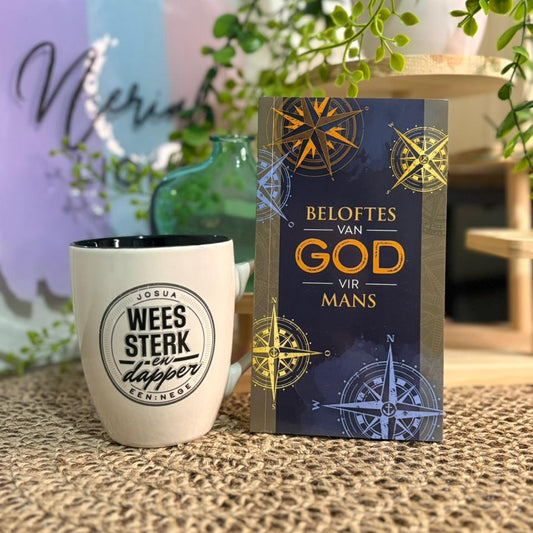 Ceramic mug with motivational quote and book titled 'Beloftes van God vir Mans' on a textured surface.